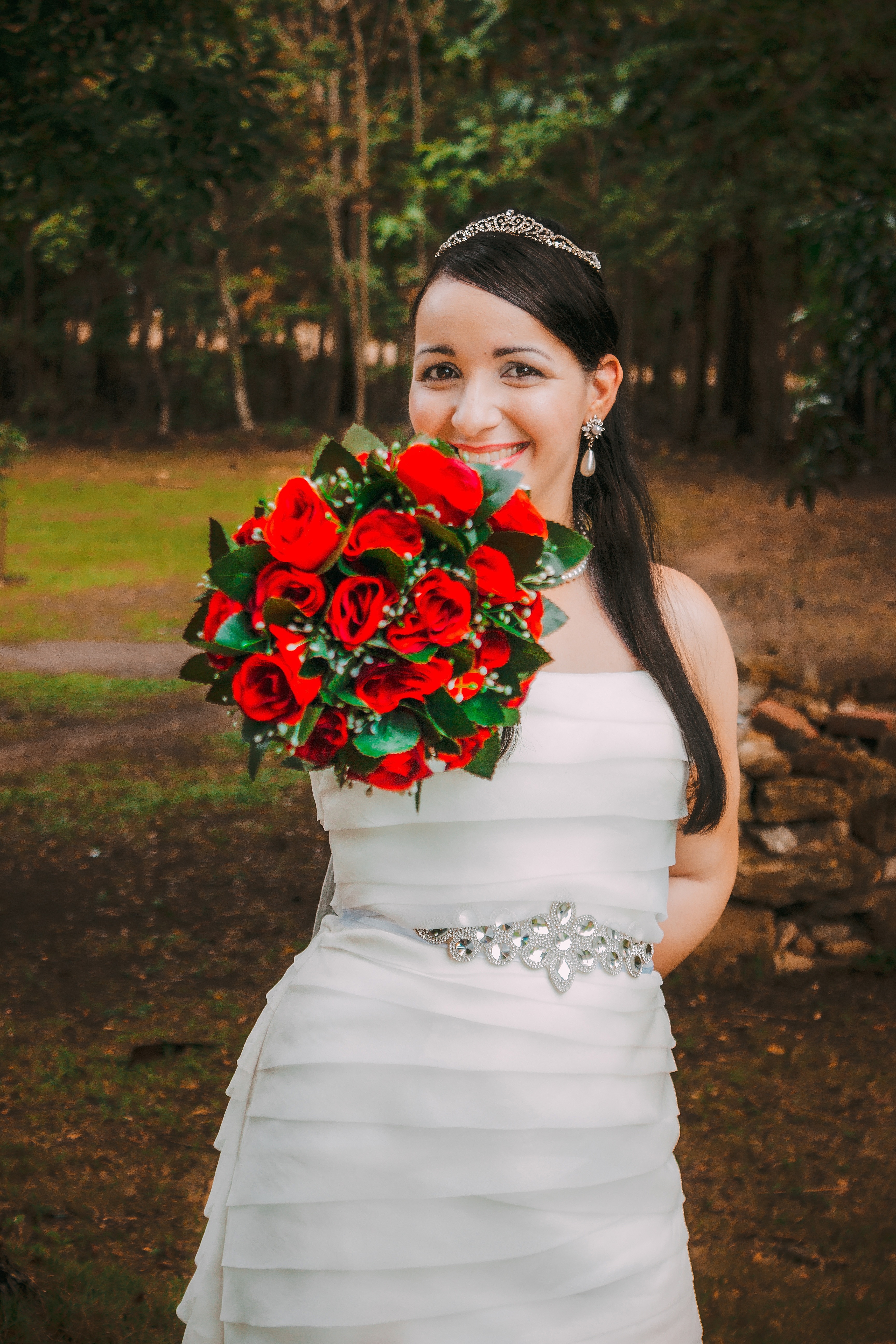 woman wearing wedding gown holding red rose bouquet