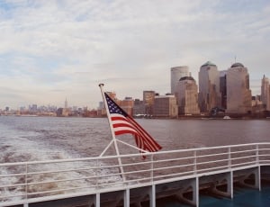 american flag on white water craft near city thumbnail