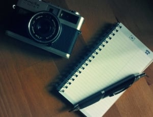white spiral notebook click pen and minolta camera thumbnail