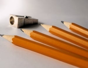 four yellow pencils beside gray metal sharpener thumbnail