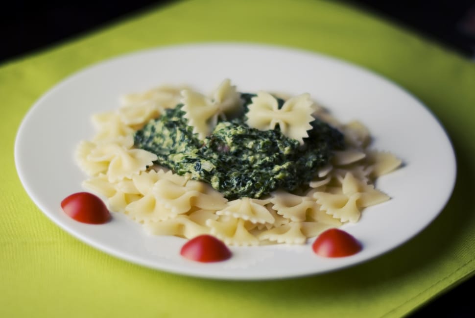 pasta with green toppings served on white ceramic plate preview