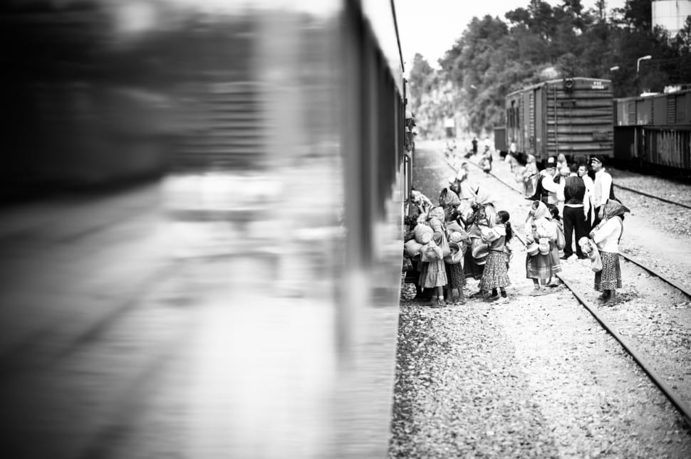 grayscale photo of children standing outside train on railway preview