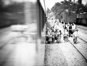 grayscale photo of children standing outside train on railway thumbnail