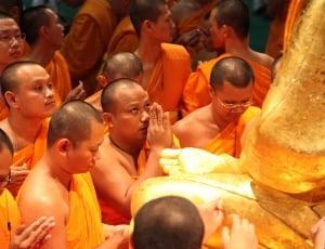 praying monks in front of statue thumbnail