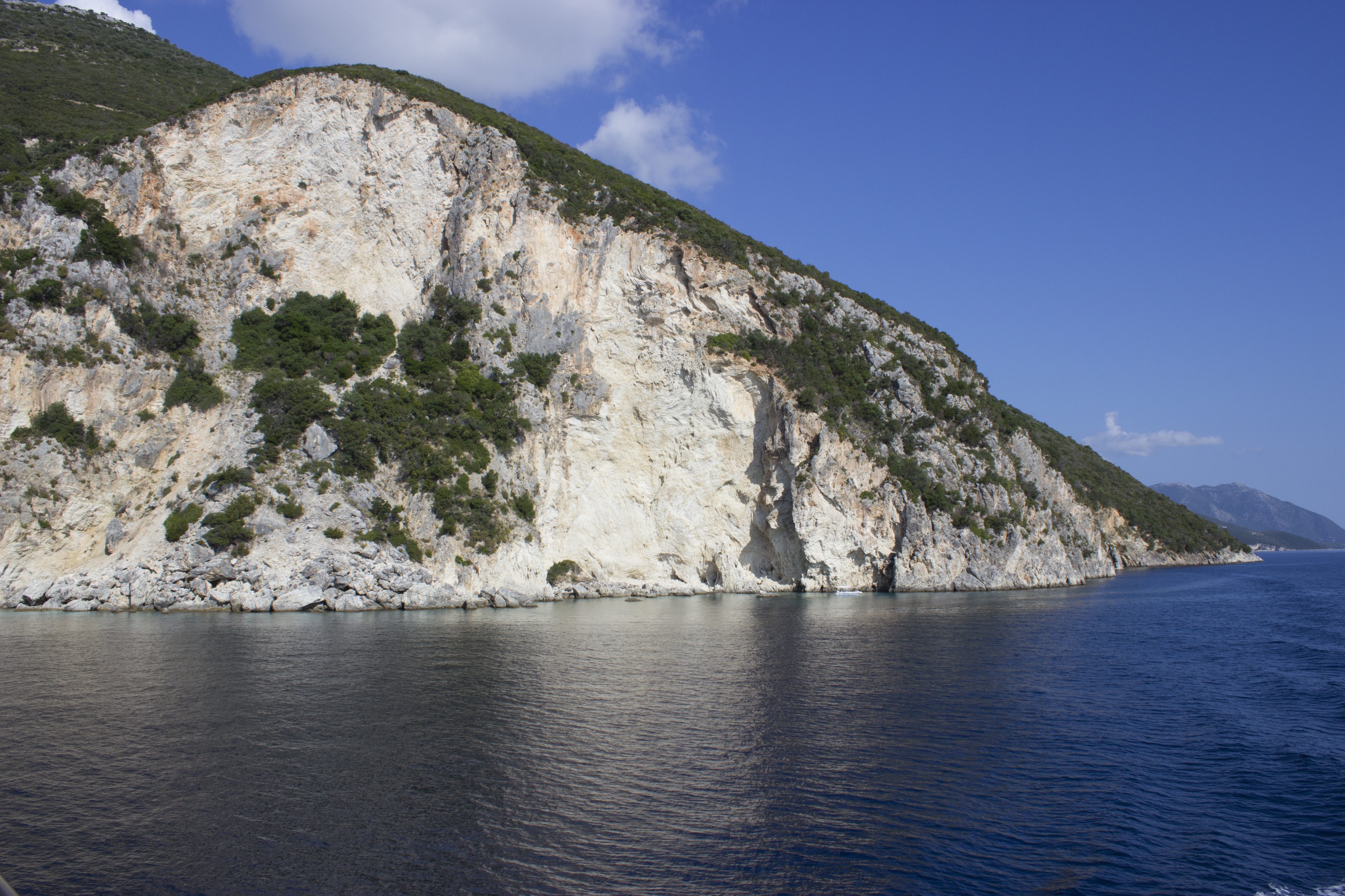 grey and brown rugged and dense hill beside blue calm body of water during daytime