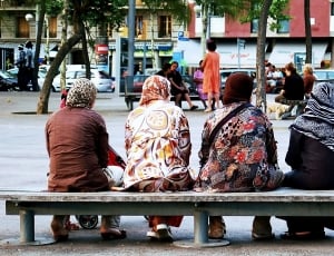 four women sitting on gray concrete bench thumbnail