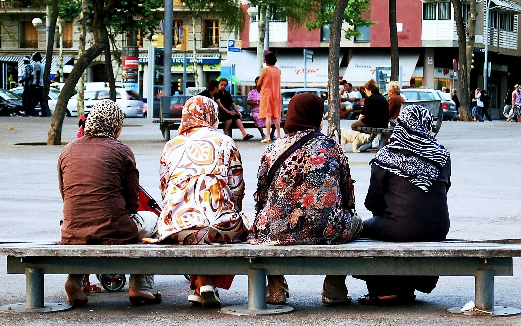 four women sitting on gray concrete bench