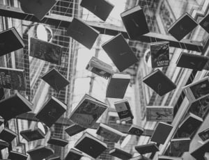 grayscale photo of assorted books hanging on the air thumbnail