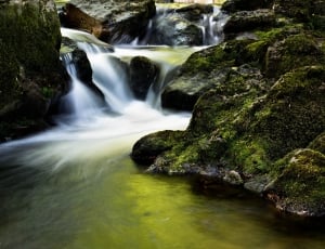 waterfalls next to rocks covered with green moss photograph thumbnail