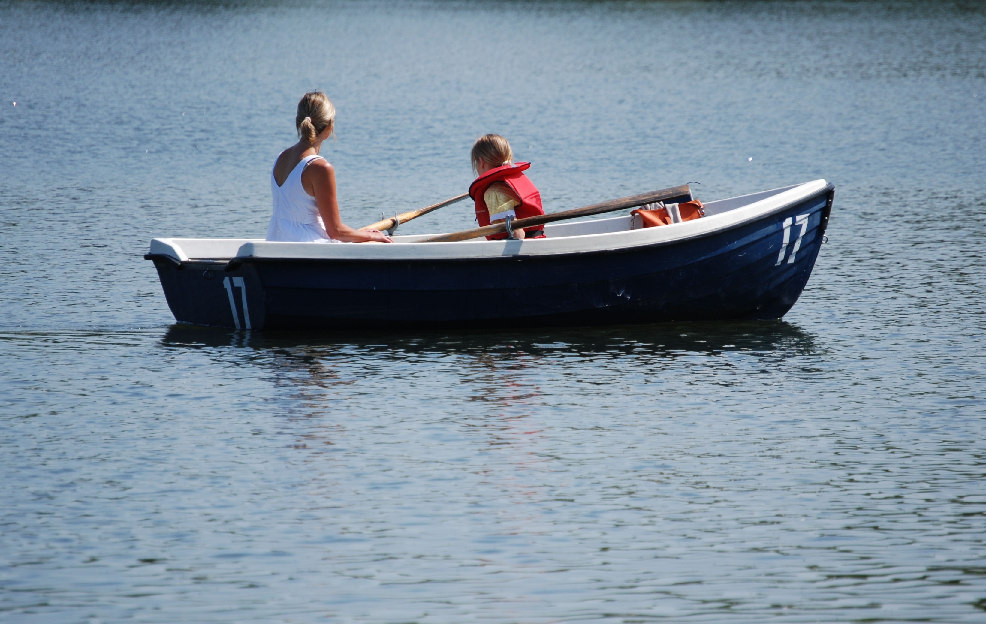 woman wearing white sleeveless shirt riding on blue and white boat