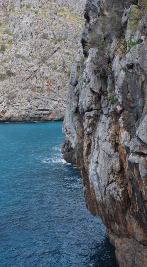 grey rocky cliff large body of water during daytime thumbnail