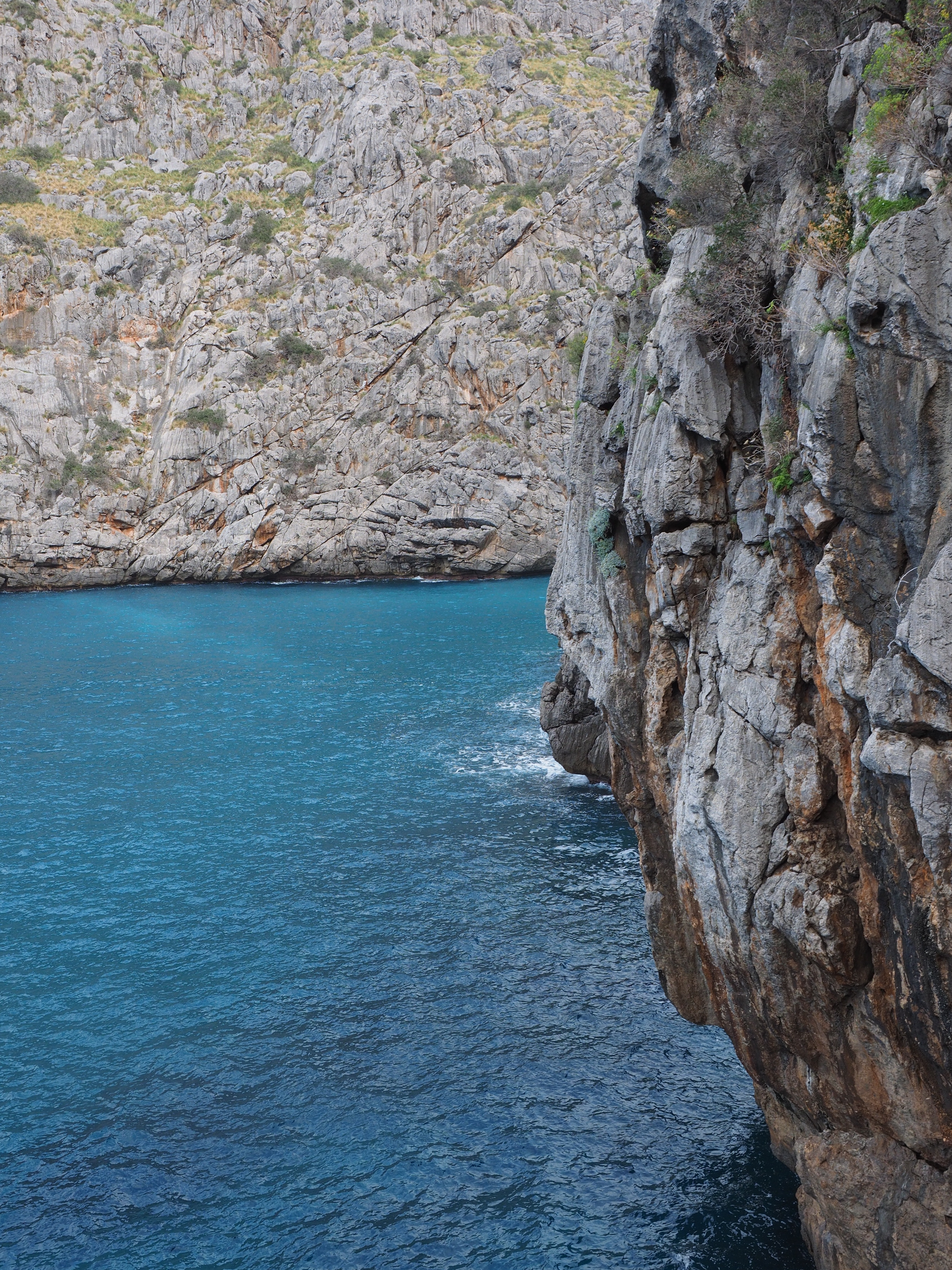 grey rocky cliff large body of water during daytime