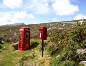 red and white phone booths on highland mountains taken during daytime thumbnail