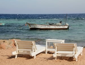 2 white wooden adirondack chairs, table and white boat thumbnail