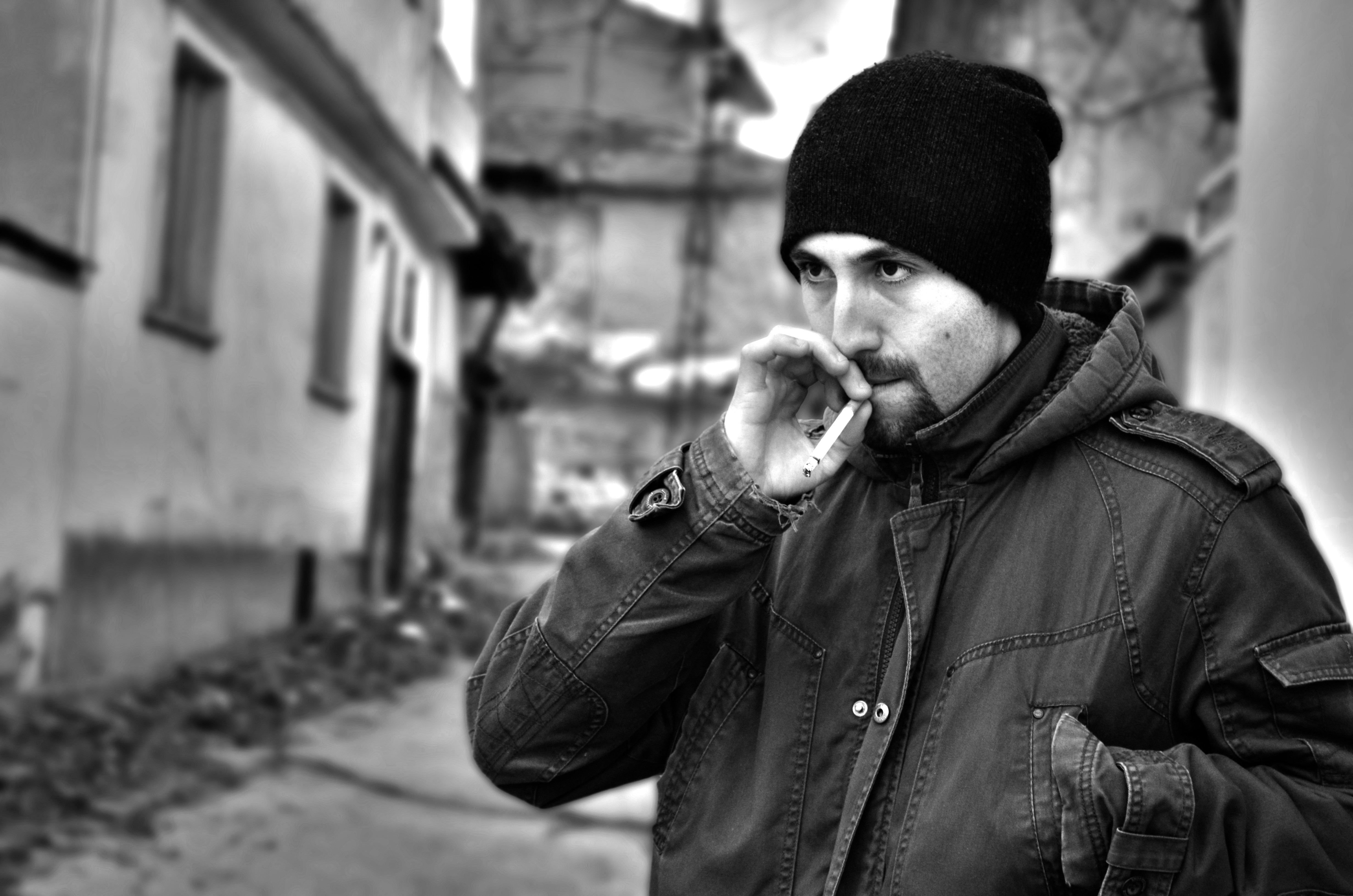 man smoking cigarette wearing knit cap near buildings