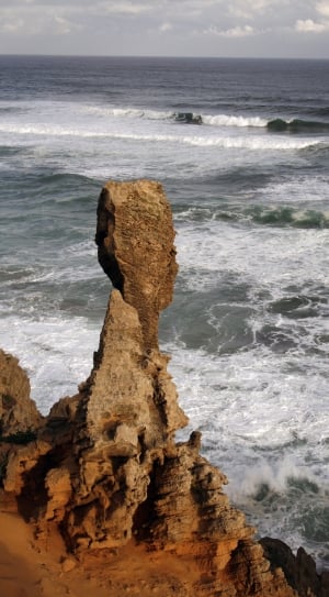 rock formation near waving seashore thumbnail