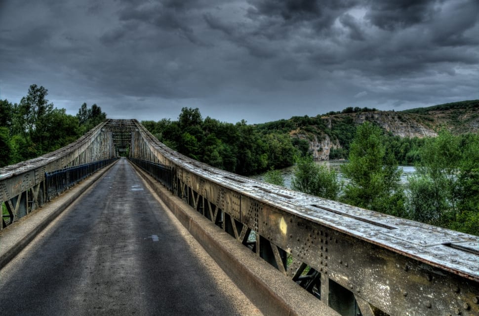 metal bridge between trees under cloudy sky preview