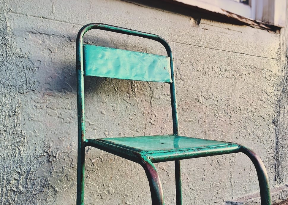 green metal chair in front of gray wall preview