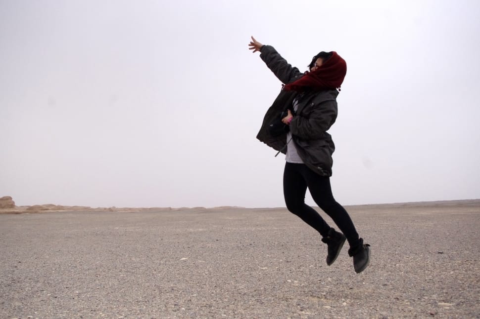 person in black jacket; black skinny jeans; red scarf jumping on air preview
