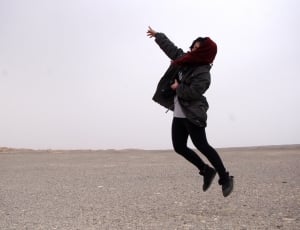 person in black jacket; black skinny jeans; red scarf jumping on air thumbnail