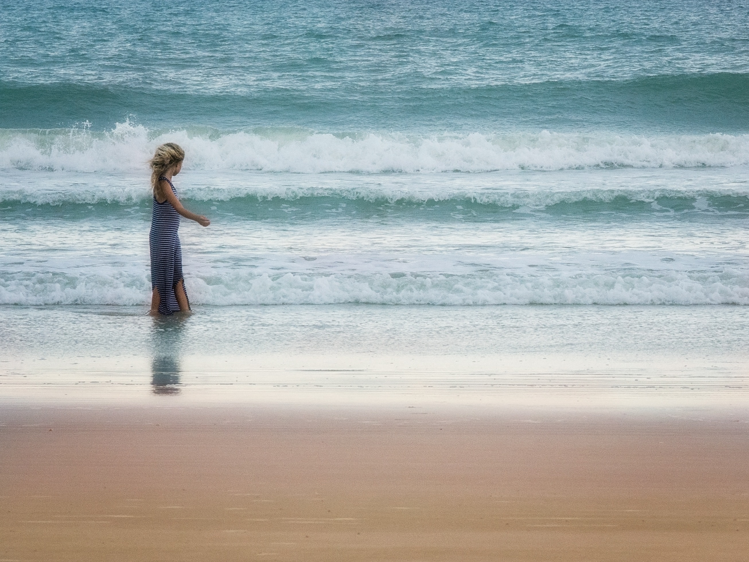 woman in blue dress standing on seashore during daytime
