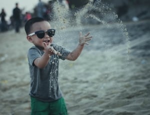 boy wearing black and white sunglasses playing sand at daytime thumbnail