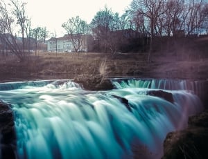 waterfalls near brown bare trees and houses thumbnail