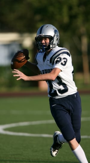 man in white and blue american football outfit holding a football while running at daytime thumbnail