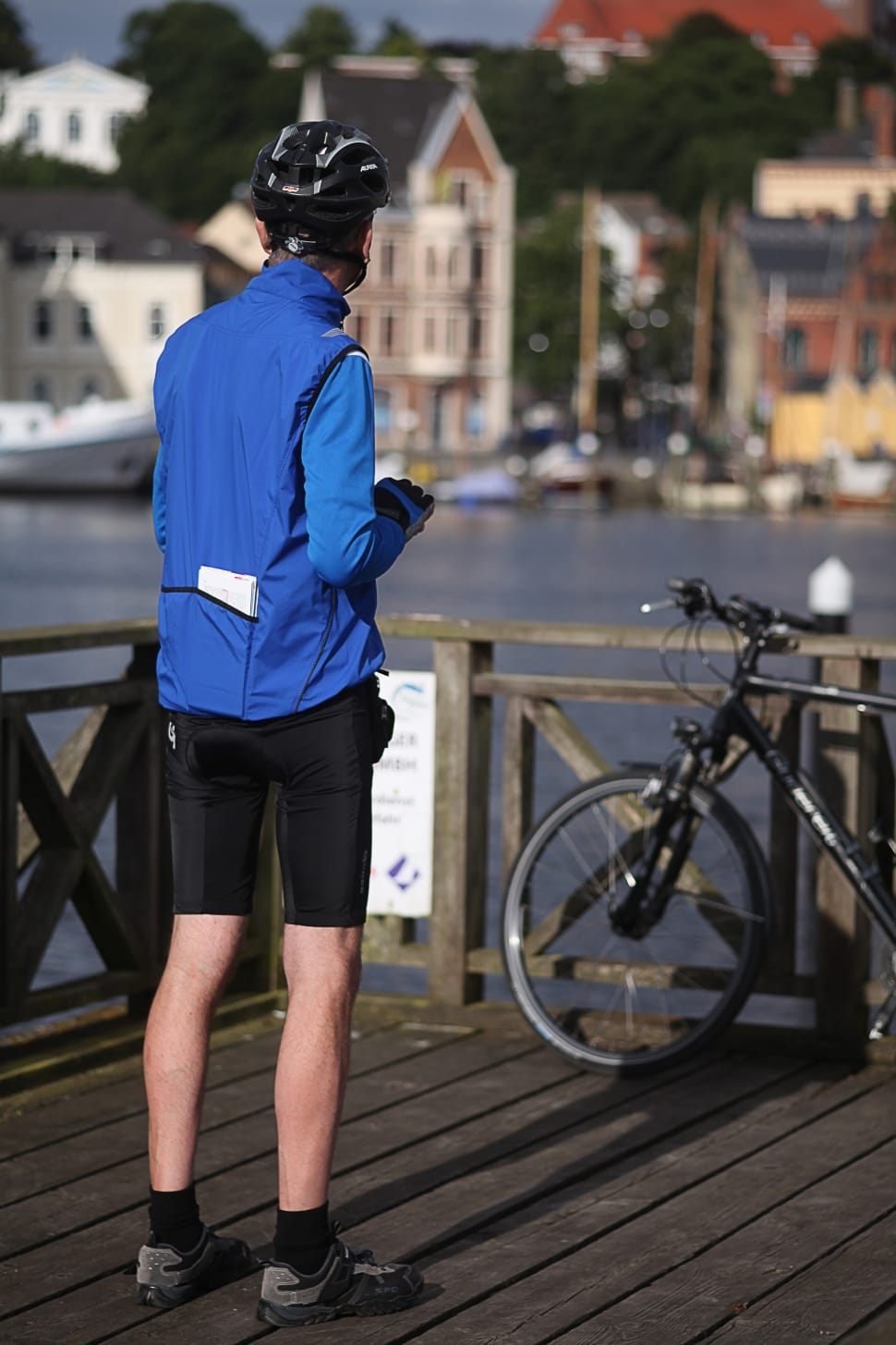 man in blue jacket and black shorts with bike helmet near body of water preview