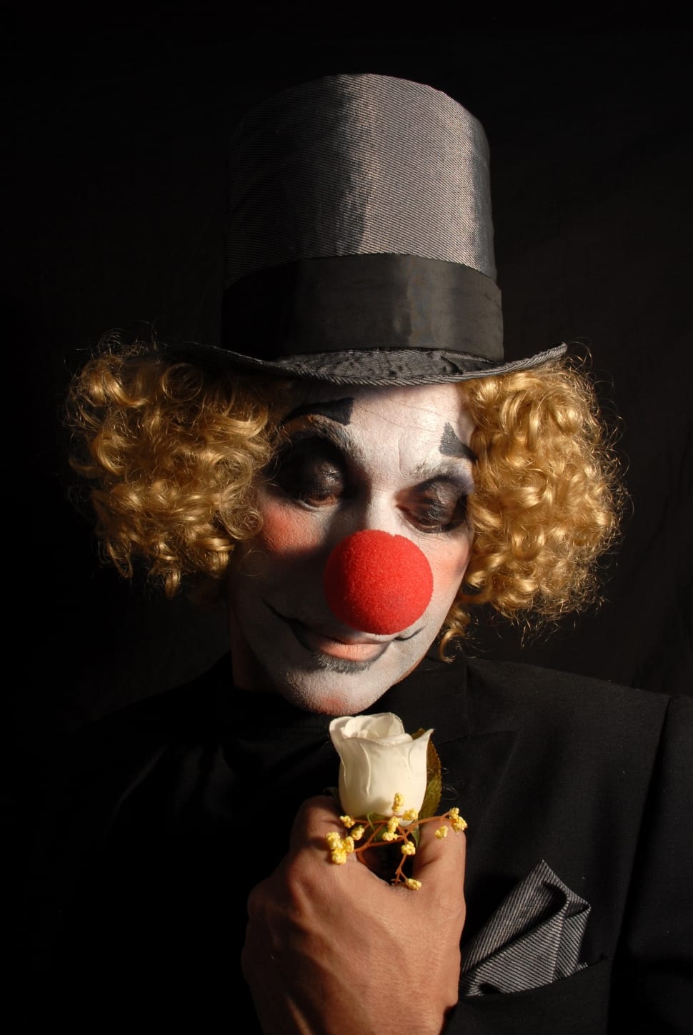 clown in black blazer holding white rose preview