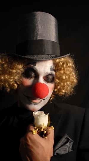 clown in black blazer holding white rose thumbnail