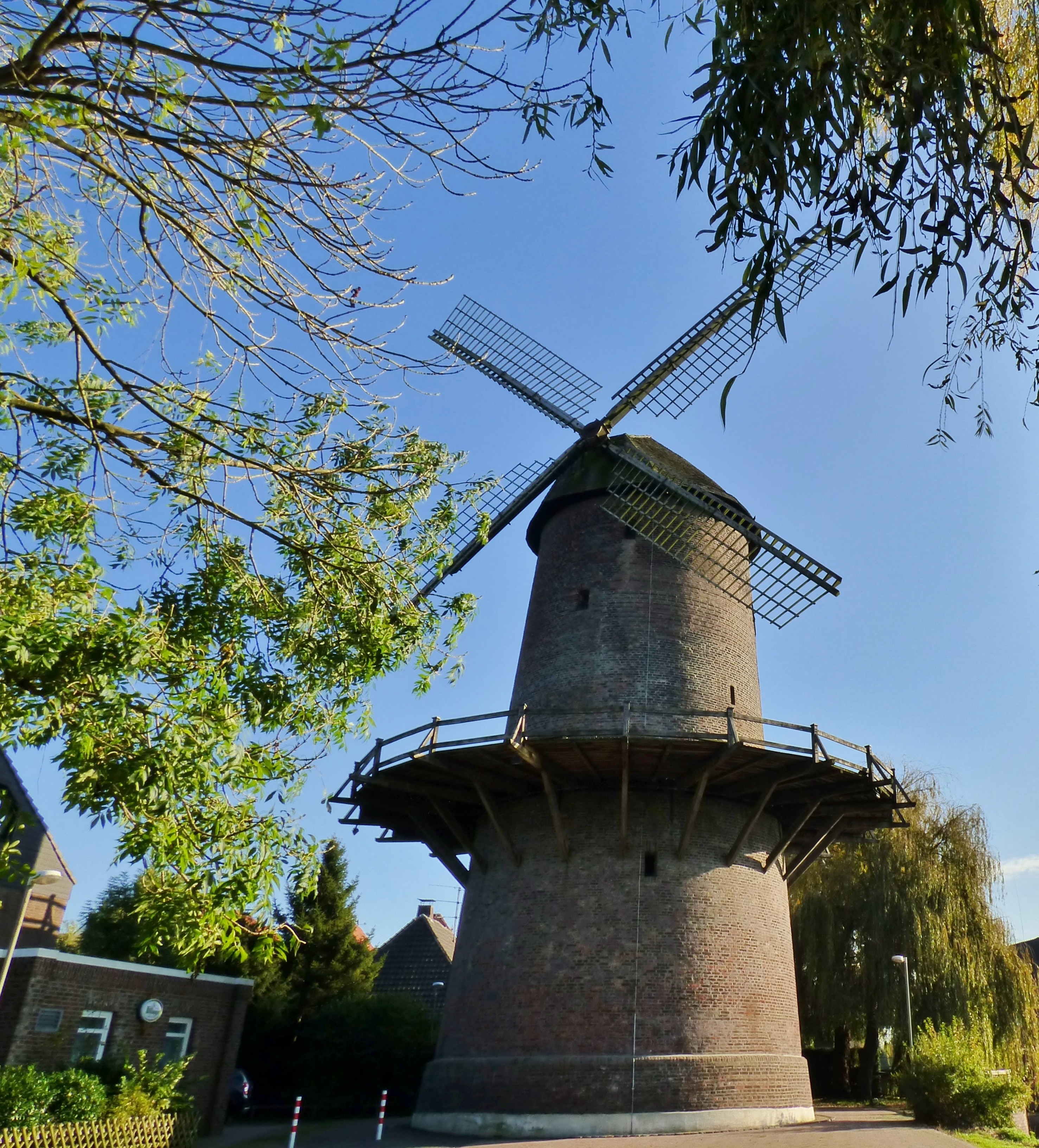 brown concrete wind mill surrounded by trees under blue sky