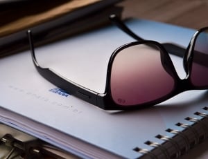 black framed sunglasses on top of notebook thumbnail