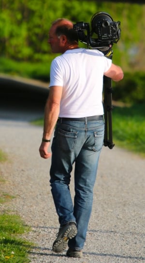 man in white shirt carrying black camera thumbnail