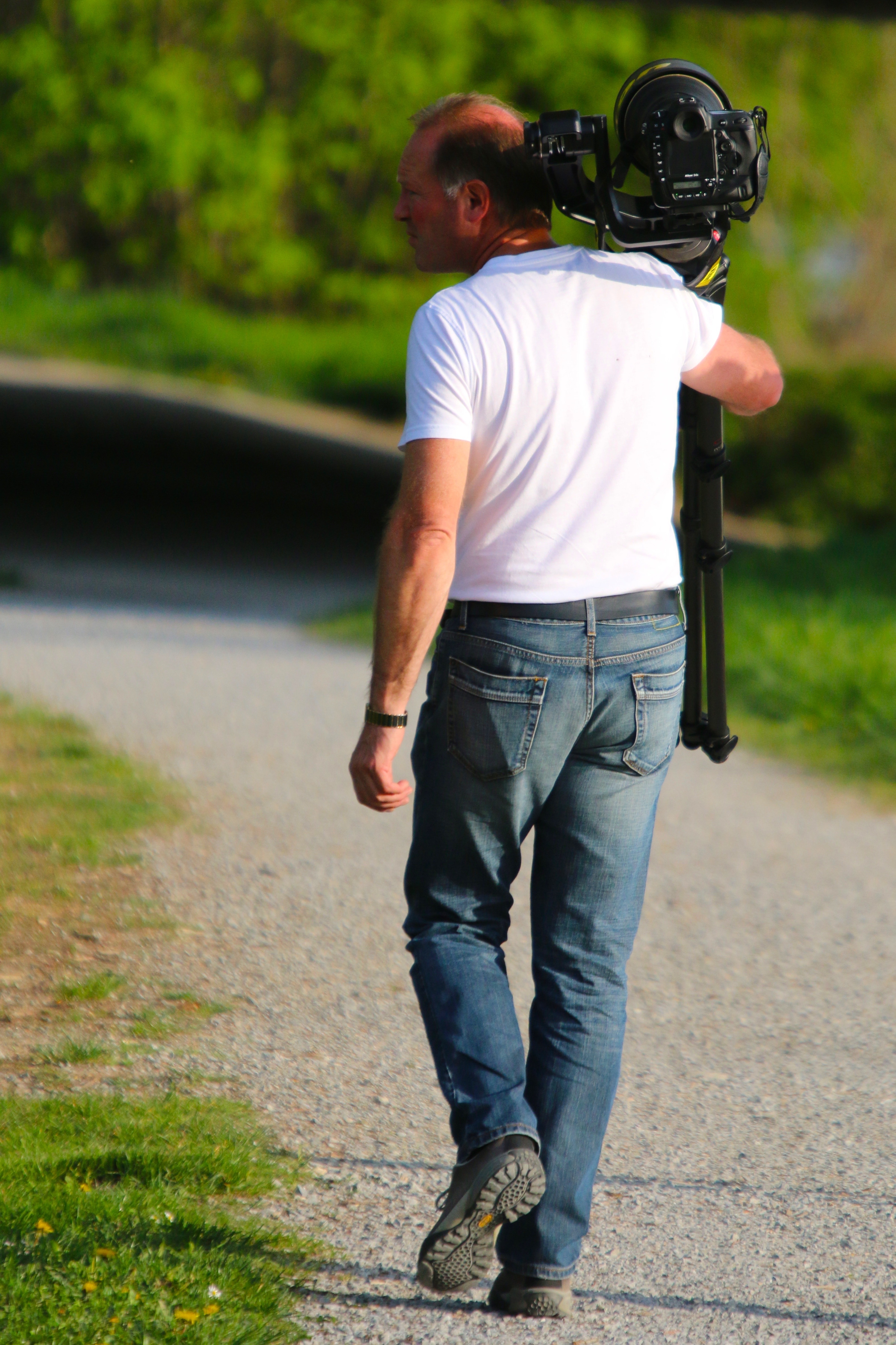 man in white shirt carrying black camera
