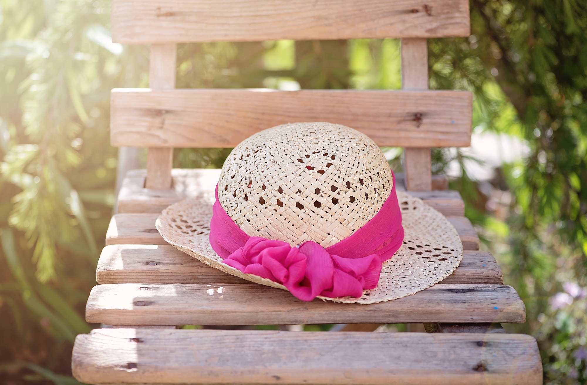 shallow focus photography of brown and pink sun hat on brown wooden chair