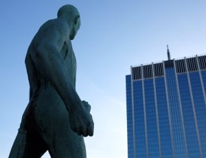 photography of man statue and blue building thumbnail