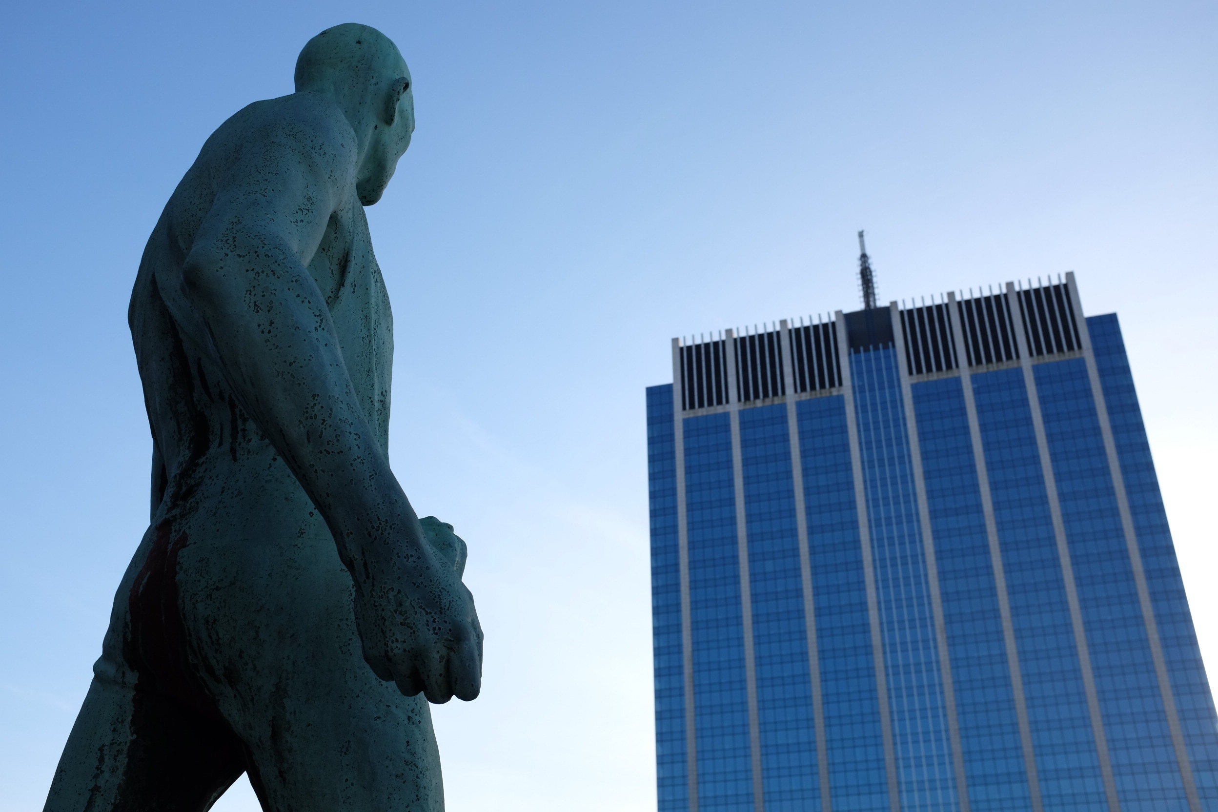 photography of man statue and blue building