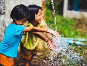 captured photo of two girls playing in a water falling from a hose thumbnail