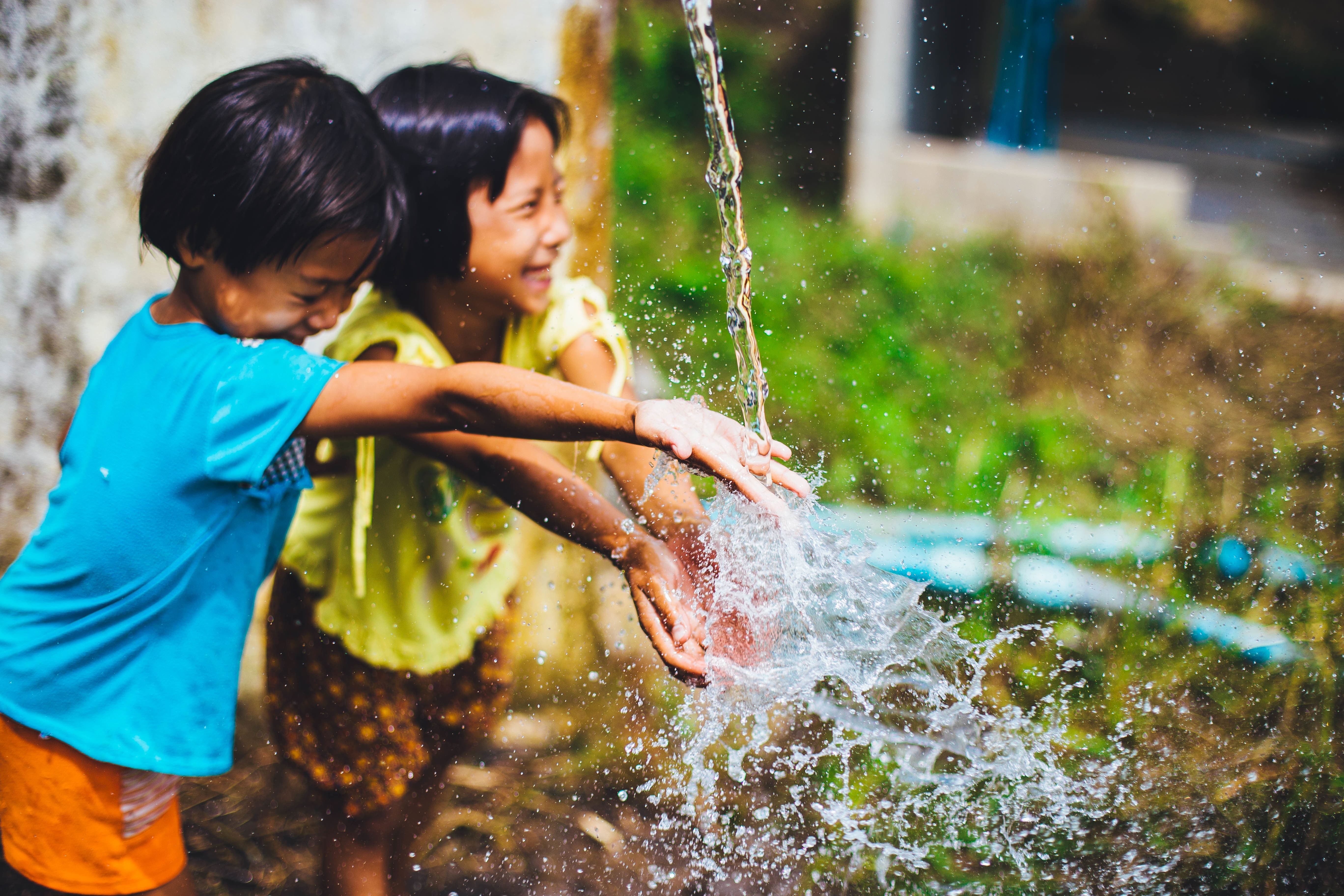 captured photo of two girls playing in a water falling from a hose
