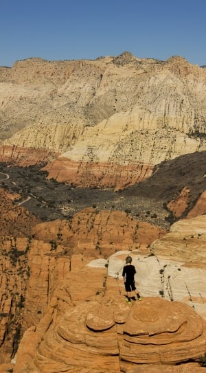 boy in black shirt standing on brown mountain during daytime thumbnail