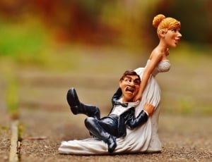 bride holding groom figurine on road during daytime thumbnail