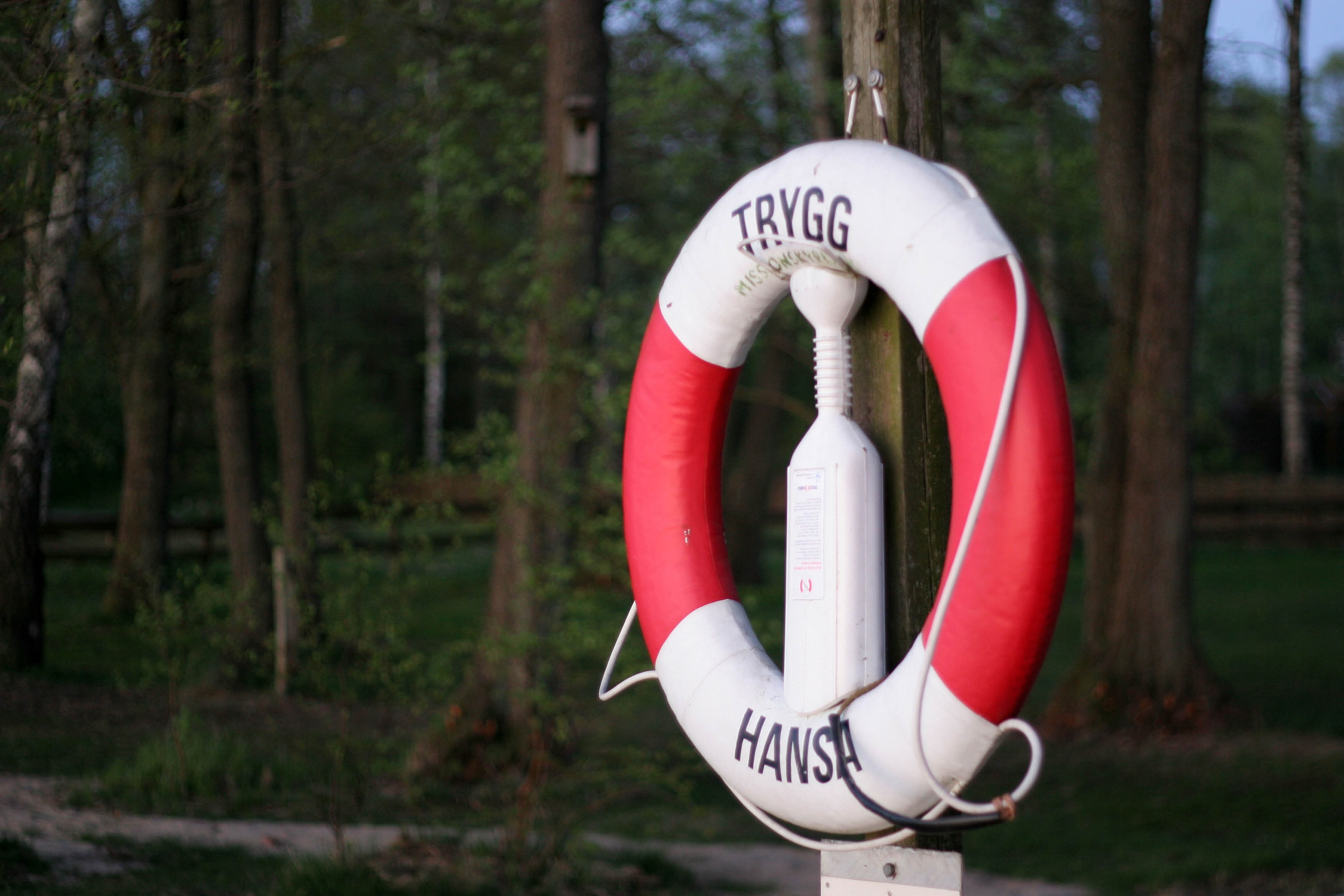 white and red  inflatable buoy hanged on brown wooden post