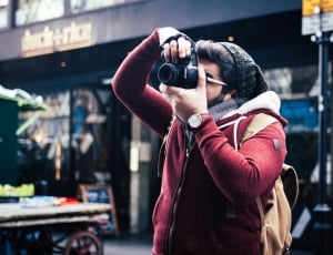 person wearing red leather jacket taking a picture during daytime thumbnail