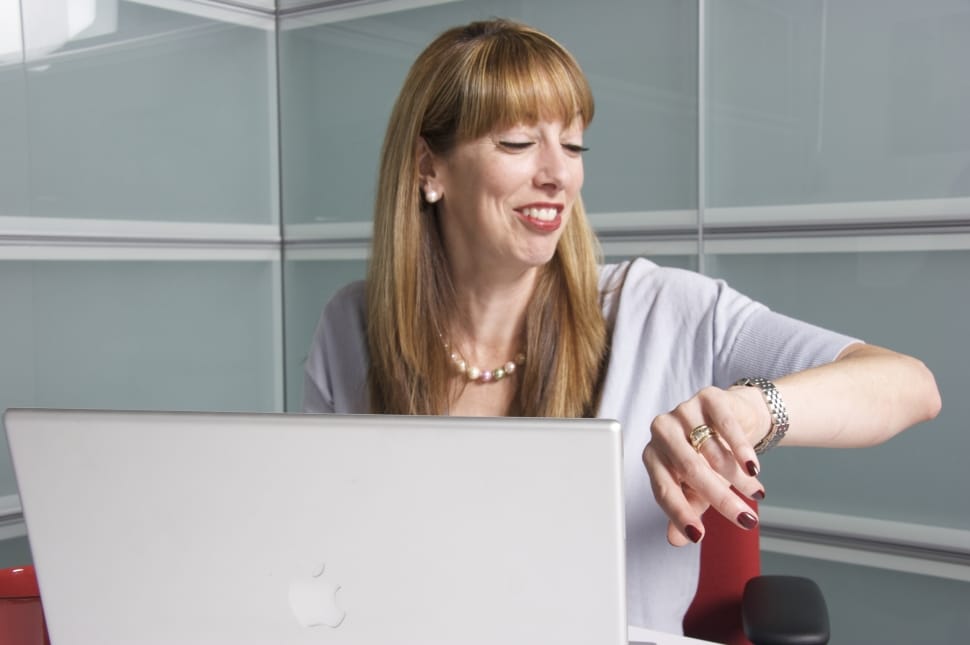 smiling woman in gray dress infront of macbook sitting on office chair preview