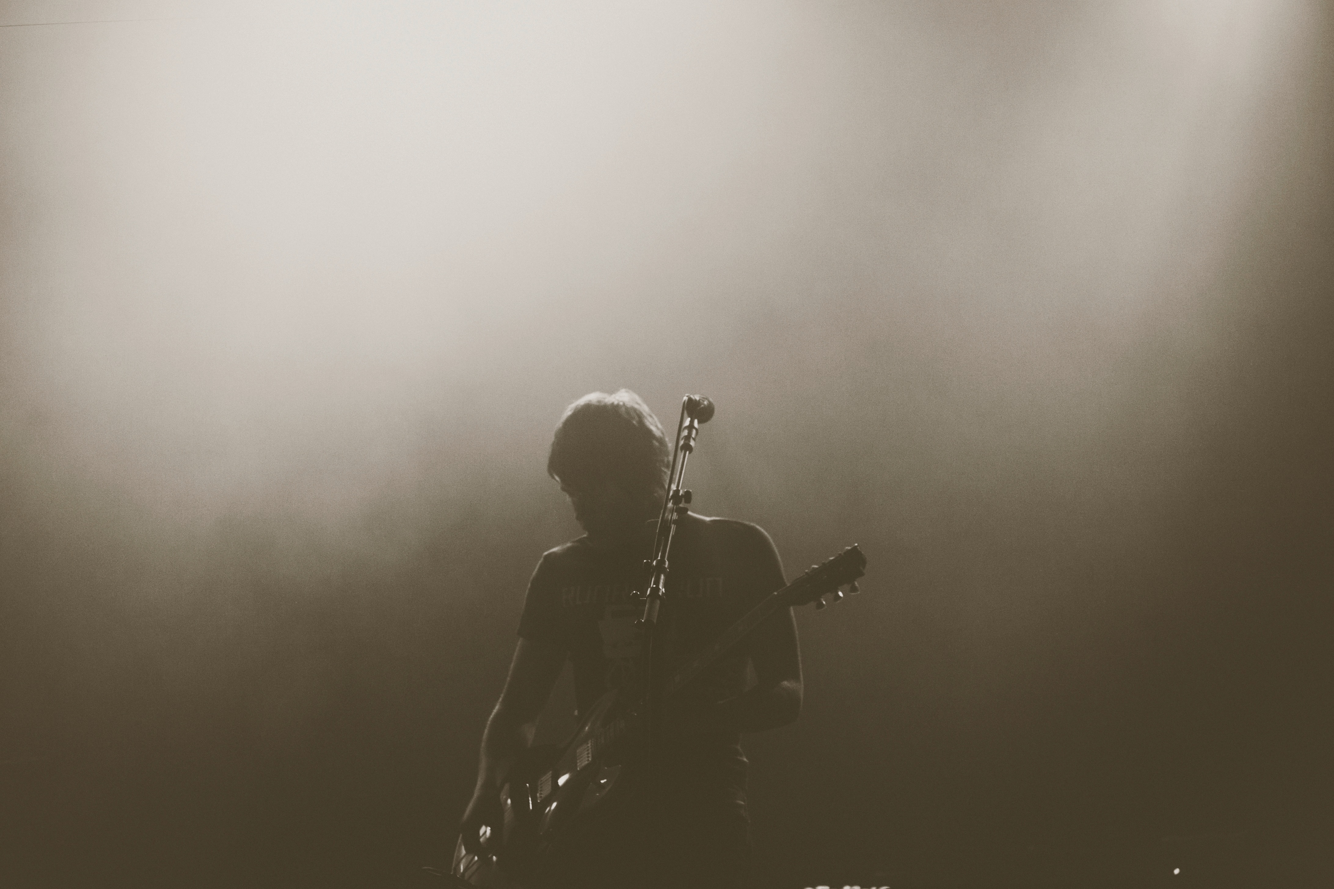 grayscale photo of man playing guitar
