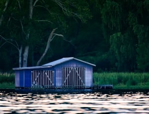 blue wooden house beside body of water thumbnail