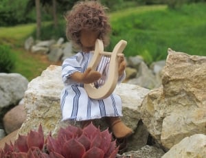 brown doll wearing white top playing harp thumbnail