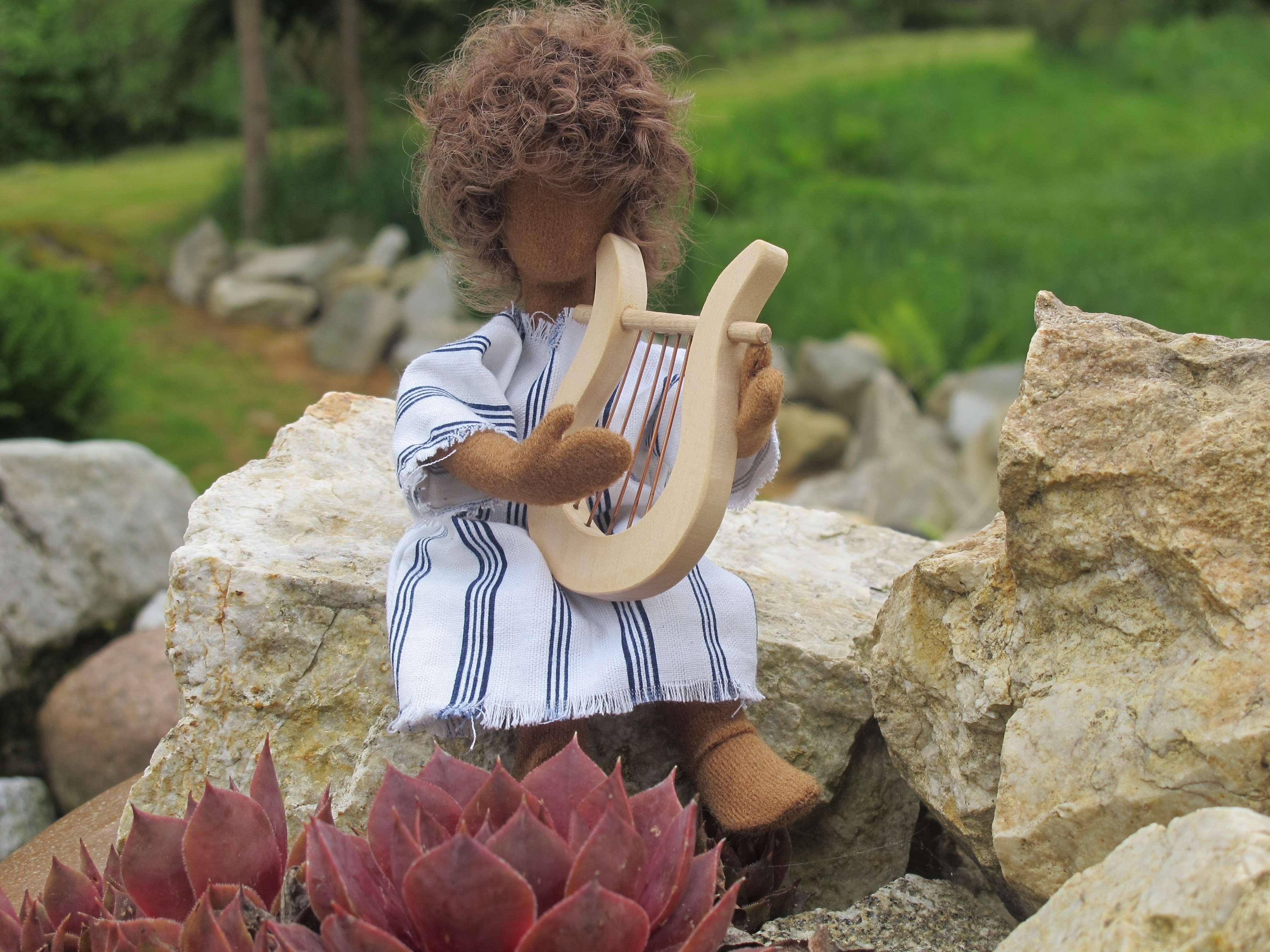 brown doll wearing white top playing harp