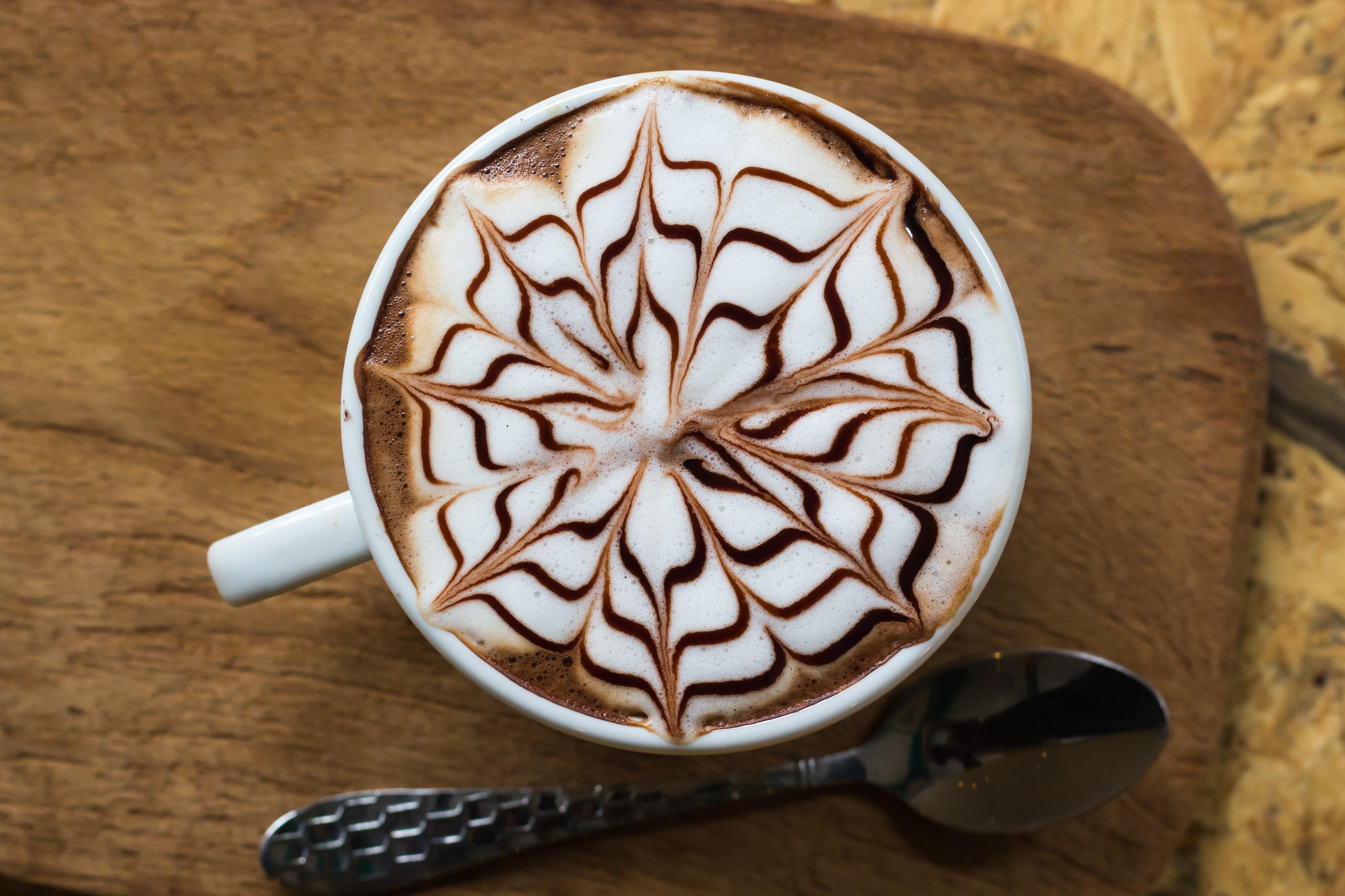 floral latte art coffee filled white ceramic mug